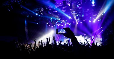 A person filming a concert on mobile phone camera. (Shutterstock Photo)