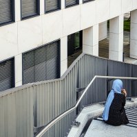 A woman wearing a headscarf sits on a staircase outside a commercial building in Munich, Germany, May 28, 2024. (AFP File Photo)