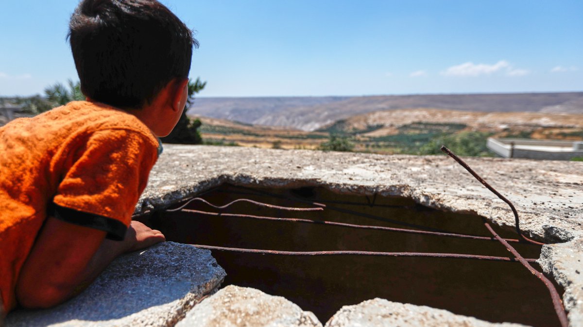 A boy looks across the landscape beside a hole left by an Israeli shell in the village of Abdin, Daraa province, Syria, June 29, 2026. (AP Photo)