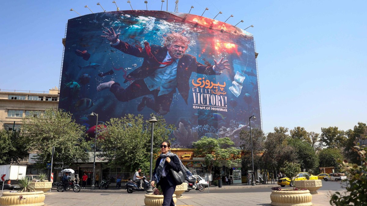 A woman walks past an anti-U.S. billboard in Tehran, Iran, Aug. 24, 2026. (AFP Photo)