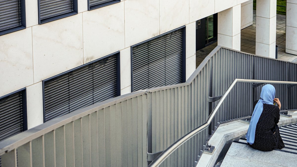A woman wearing a headscarf sits on a staircase outside a commercial building in Munich, Germany, May 28, 2024. (AFP File Photo)