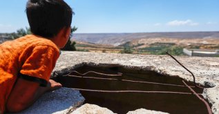 A boy looks across the landscape beside a hole left by an Israeli shell in the village of Abdin, Daraa province, Syria, June 29, 2026. (AP Photo)