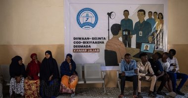 People wait to register to vote at a registration center in front of a National Independent Electoral Boundaries Commission poster, Mogadishu, Somalia, April 23, 2025. (Getty Images Photo)