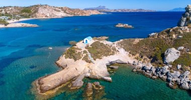 An aerial view of a small white-and-blue church on an islet off Agios Stefanos Beach, Kos, Greece. (Shutterstock Photo)