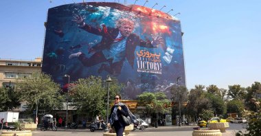A woman walks past an anti-U.S. billboard in Tehran, Iran, Aug. 24, 2026. (AFP Photo)