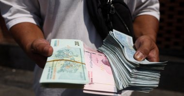 A currency dealer holds Iranian rial in the Grand Bazaar in Tehran, Iran, Aug. 17, 2026. (Reuters Photo)