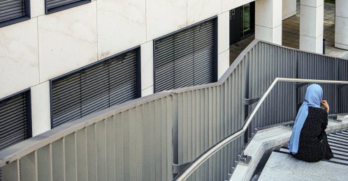 A woman wearing a headscarf sits on a staircase outside a commercial building in Munich, Germany, May 28, 2024. (AFP File Photo)