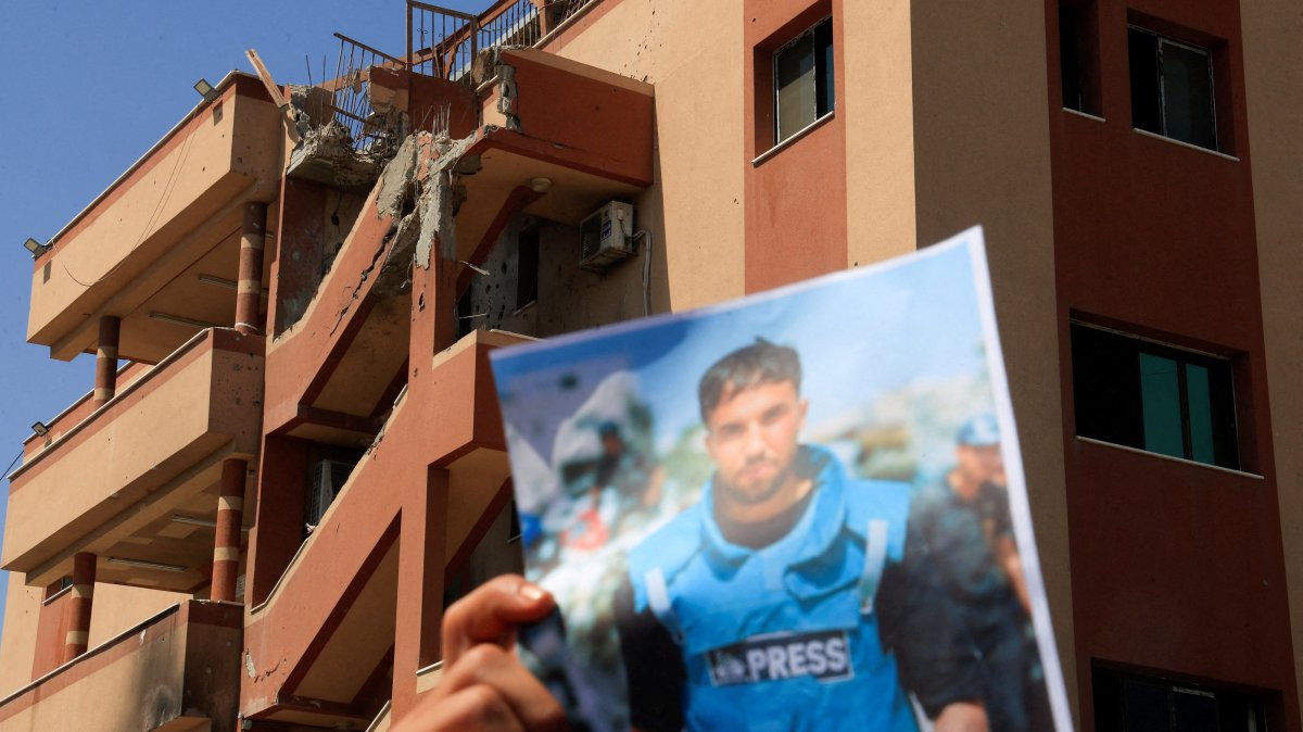 A damaged building in the background while a person holds a picture of Moaz Abu Taha, as Palestinian journalists take part in a solidarity vigil to commemorate their colleagues killed during an Israeli strike at Nasser Hospital, on the first anniversary of their killing, in Khan Younis, southern Gaza Strip, Palestine, Aug. 25, 2026. (Reuters Photo)