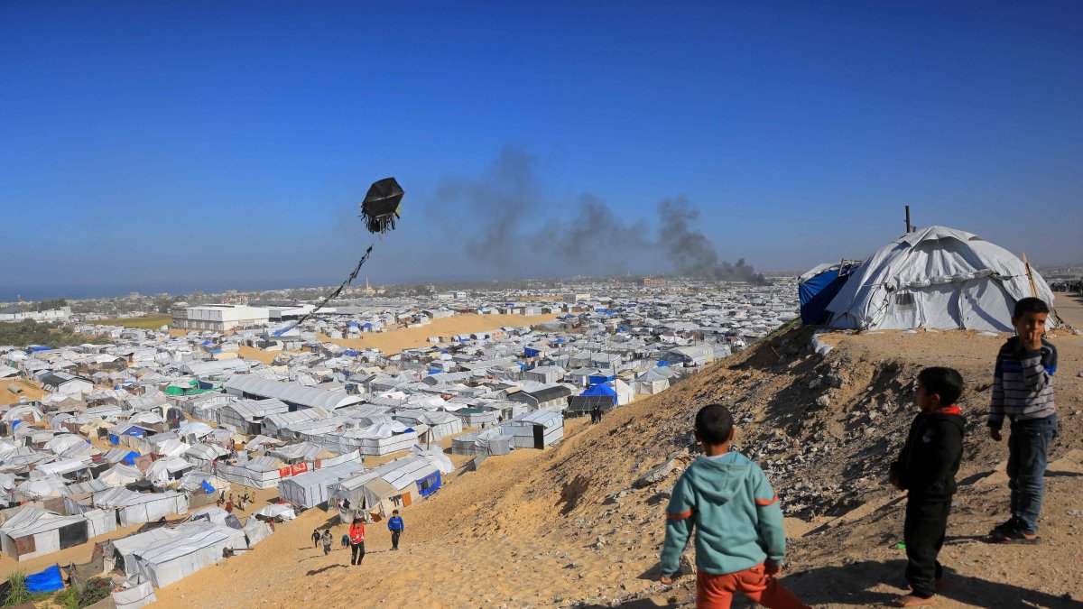Boys fly a kite against the backdrop of smoke rising from the Gath shelter, that houses displaced Palestinians, after an Israeli air strike in the west of Khan Younis, southern Gaza Strip, Jan. 31, 2026. (AFP File Photo)