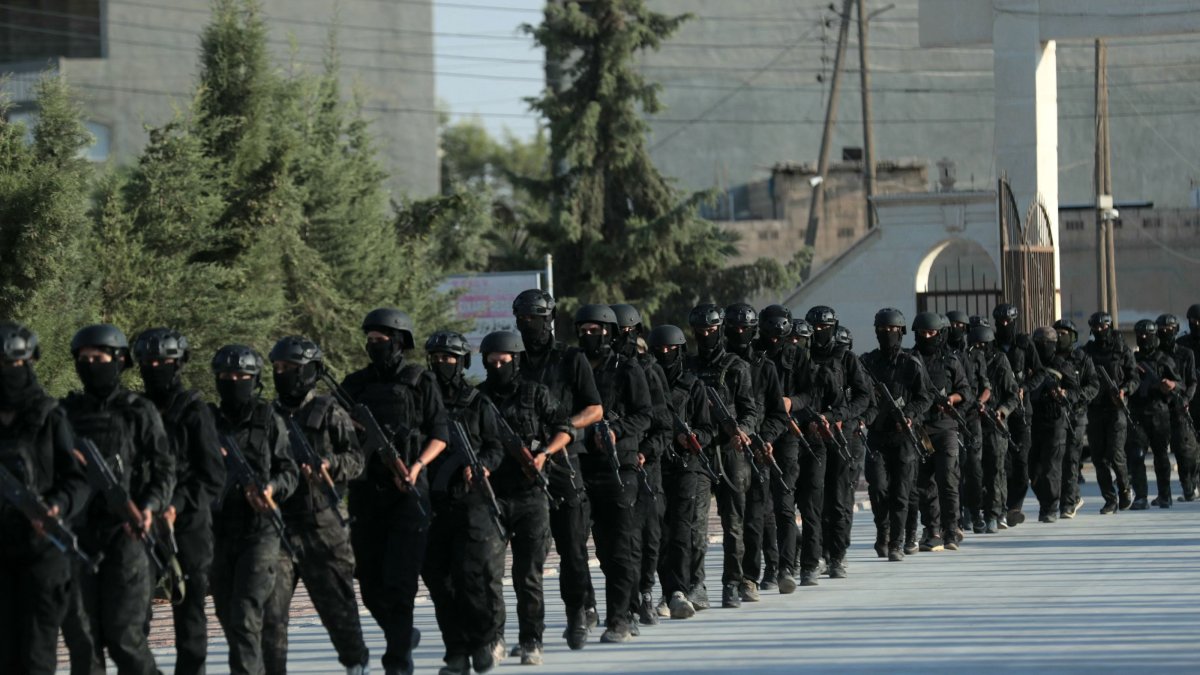 Kurdish fighters from the Qamishli Brigade, part of the Syrian Democratic Forces (SDF) participate in a military parade in Qamishli on August 21, 2026, during the funeral ceremony for three Kurdish fighters killed in previous battles in Aleppo's Sheikh Maqsoud neighbourhood in the north of Syria. (Photo by Delil SOULEIMAN / AFP)