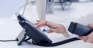 A customer service representative handles a phone call at a help desk. (Shutterstock Photo) 