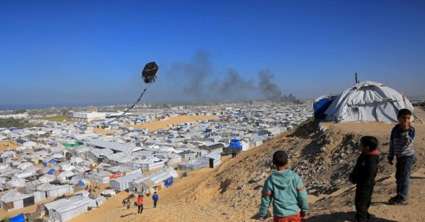 Boys fly a kite against the backdrop of smoke rising from the Gath shelter, that houses displaced Palestinians, after an Israeli air strike in the west of Khan Younis, southern Gaza Strip, Jan. 31, 2026. (AFP File Photo)