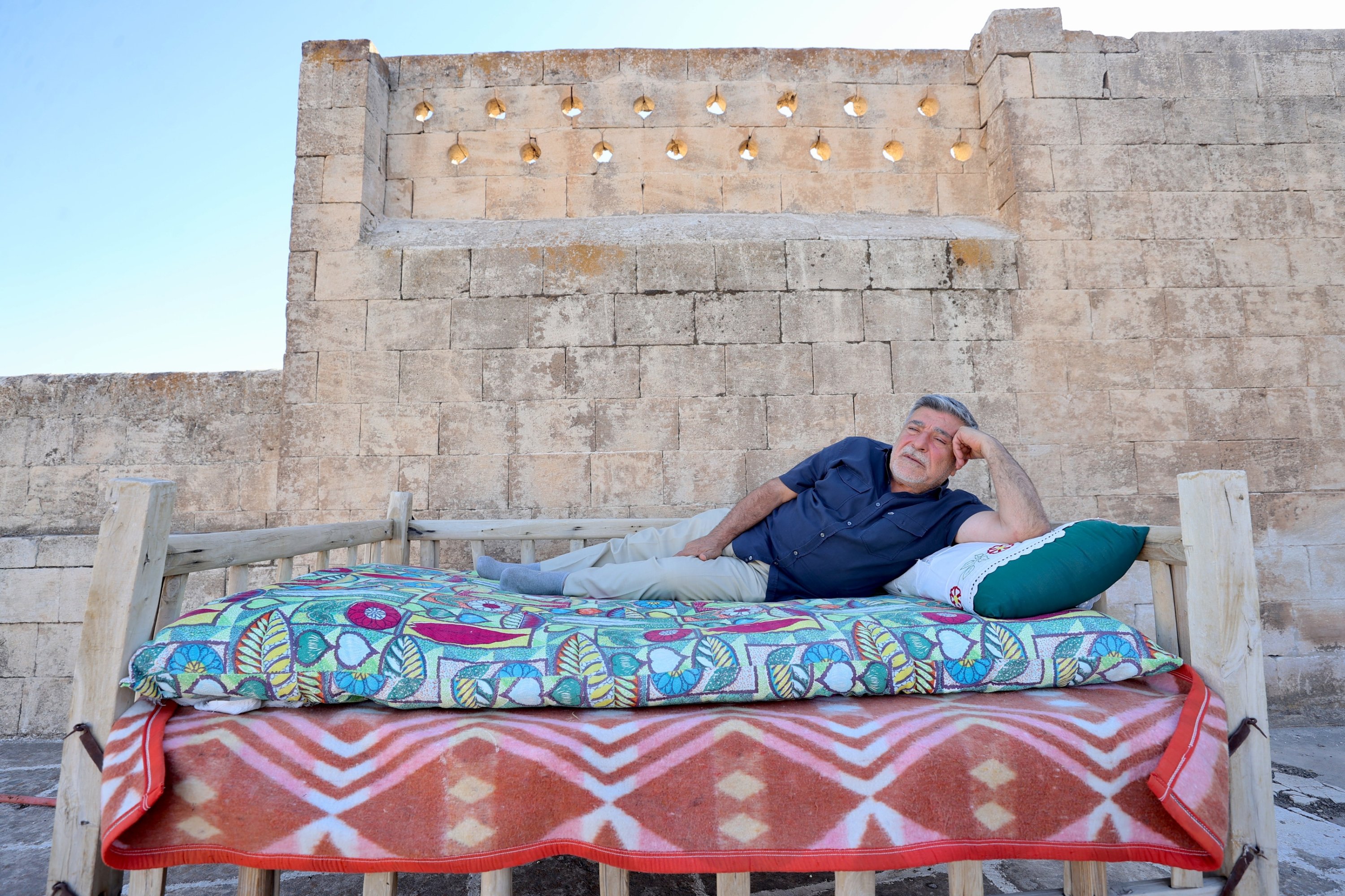A resident lies on a traditional rooftop platform to cool off during a hot summer evening, Mardin, southeastern Türkiye, Aug. 4, 2026. (AA Photo)
