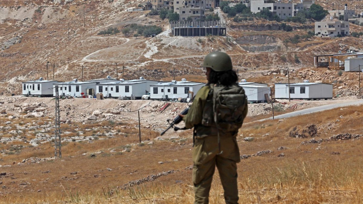 An Israeli soldier stands guard against the backdrop of an illegal Israeli settlement outpost in Beit Sahur, south of Bethlehem, in the occupied West Bank, Aug.14, 2026. (AFP Photo)