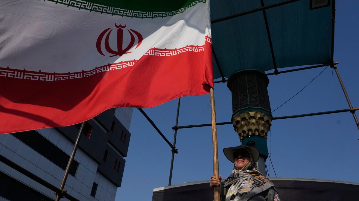 A woman flies an Iranian flag in downtown Tehran, Iran, Monday, Aug. 17, 2026. (AP Photo)