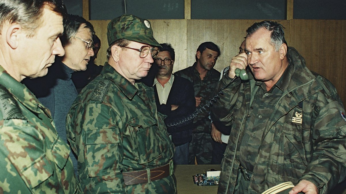 Former Bosnian military Serb leader and war criminal Ratko Mladic (R) talks on the phone next to Russian Army General Vladimir Zurbenko (C) during the visit of a Russian Army delegation to the Bosnian town of Banja Luka, Bosnia-Herzegovina, Oct. 1995. (AP Photo)