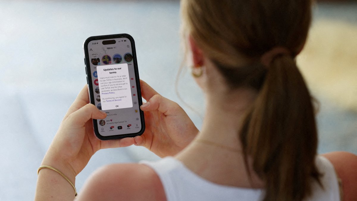 A teenager poses holding a mobile phone in Sydney, Australia, Dec. 10, 2025. (Reuters Photo)