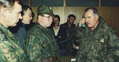 Former Bosnian military Serb leader and war criminal Ratko Mladic (R) talks on the phone next to Russian Army General Vladimir Zurbenko (C) during the visit of a Russian Army delegation to the Bosnian town of Banja Luka, Bosnia-Herzegovina, Oct. 1995. (AP Photo)