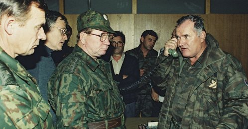 Former Bosnian military Serb leader and war criminal Ratko Mladic (R) talks on the phone next to Russian Army General Vladimir Zurbenko (C) during the visit of a Russian Army delegation to the Bosnian town of Banja Luka, Bosnia-Herzegovina, Oct. 1995. (AP Photo)