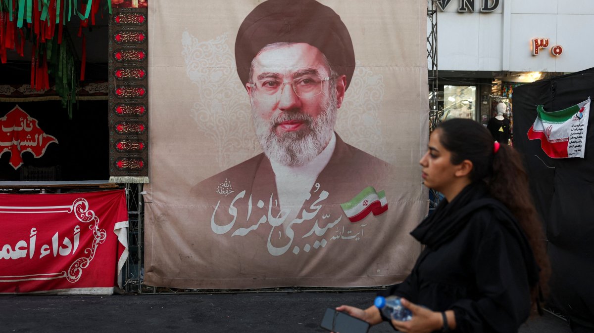 A woman walks next to a banner with a picture of Iran's Supreme Leader Mojtaba Khamenei in Tehran, Iran, Aug. 13, 2026. (Reuters Photo)