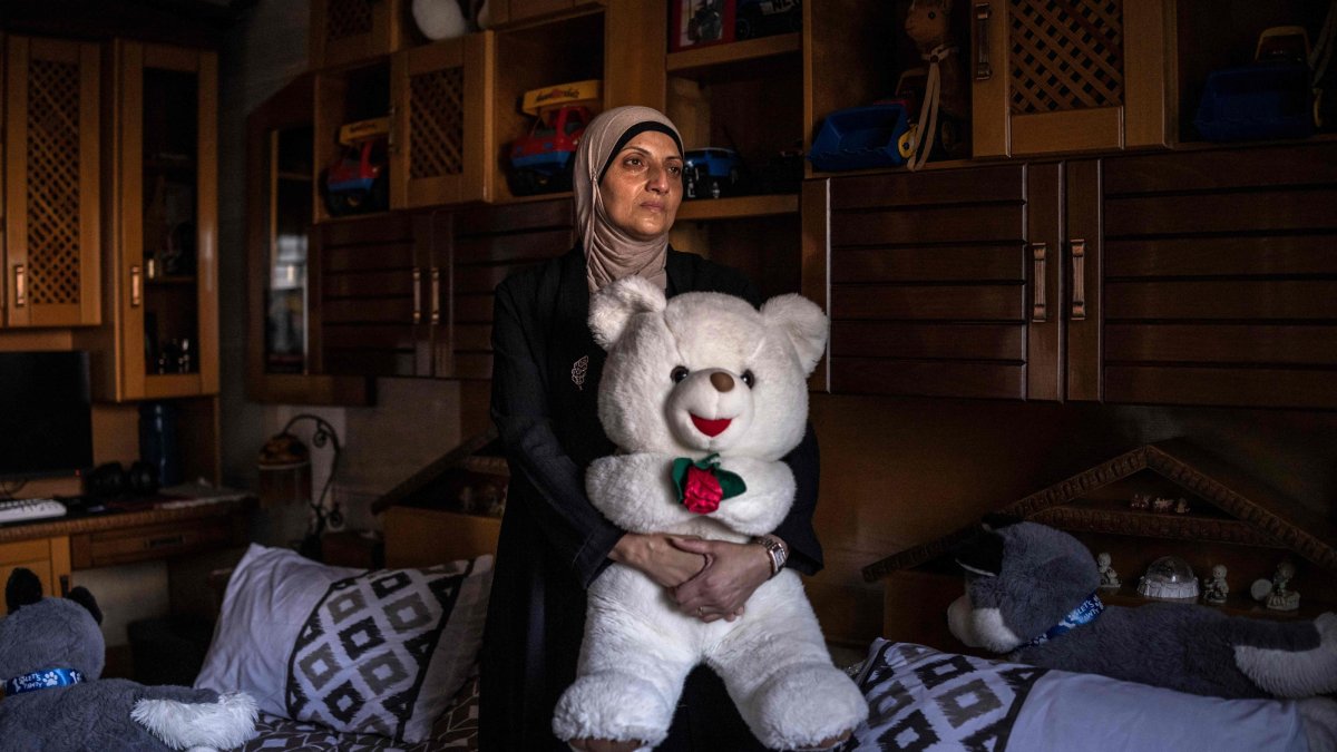 Kholoud Mamadneh, mother of 15-year-old Mahmoud Mamadneh, who was killed by Israeli forces on his way back from school, holds a teddy bear her son had as a baby as she stands for a portrait in front of his bed in Jenin, in the Israeli-occupied West Bank, July 27, 2026. (AFP Photo)