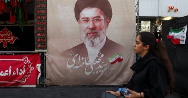 A woman walks next to a banner with a picture of Iran's Supreme Leader Mojtaba Khamenei in Tehran, Iran, Aug. 13, 2026. (Reuters Photo)