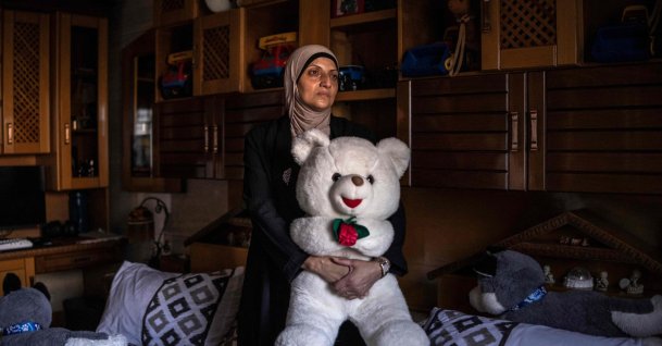 Kholoud Mamadneh, mother of 15-year-old Mahmoud Mamadneh, who was killed by Israeli forces on his way back from school, holds a teddy bear her son had as a baby as she stands for a portrait in front of his bed in Jenin, in the Israeli-occupied West Bank, July 27, 2026. (AFP Photo)