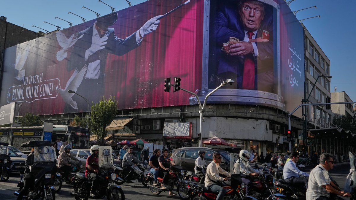 Motorcyclists ride past a billboard depicting U.S. President Donald Trump inside a catering container in downtown Tehran, Iran, Saturday, Aug. 29, 2026. (AP Photo/Vahid Salemi)