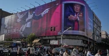 Motorcyclists ride past a billboard depicting U.S. President Donald Trump inside a catering container in downtown Tehran, Iran, Saturday, Aug. 29, 2026. (AP Photo/Vahid Salemi)