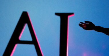 AI (Artificial Intelligence) letters and a miniature robot hand are seen in this illustration created June 23, 2023. (Reuters Photo)