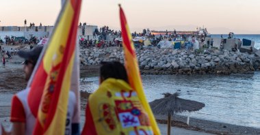 Anti-migrant demonstrators look toward migrants camping on the Trampolin beach in Ceuta, Spain, Aug. 28, 2026. (AFP Photo)