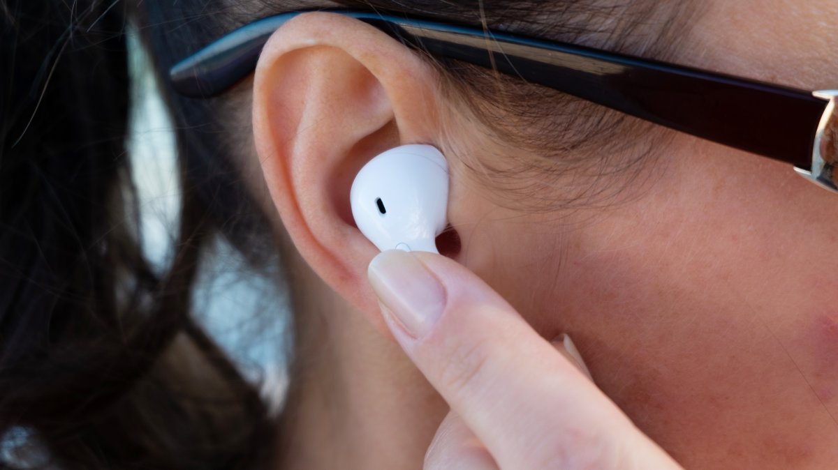 A closeup view of a girl putting on wireless earphones. (Shutterstock Photo)