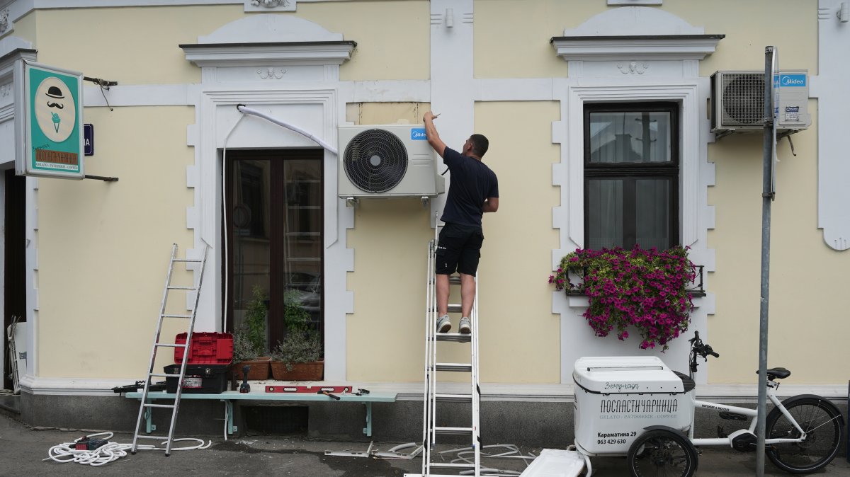 A worker installs a new air conditioning unit during a hot summer day, Belgrade, Serbia, June 30, 2026. (AP File Photo)