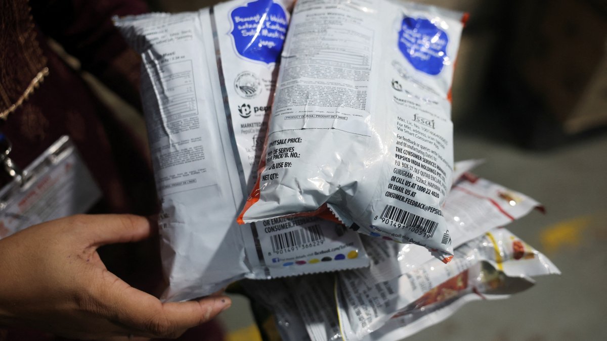 A Maharashtra Food and Drug Administration (FDA) official displays Kurkure snack packets with erased expiry dates, prices and other product details, and with new labels bearing altered ingredient information, during a raid at a warehouse, Turbhe, India, Aug. 25, 2026. (Reuters Photo)
