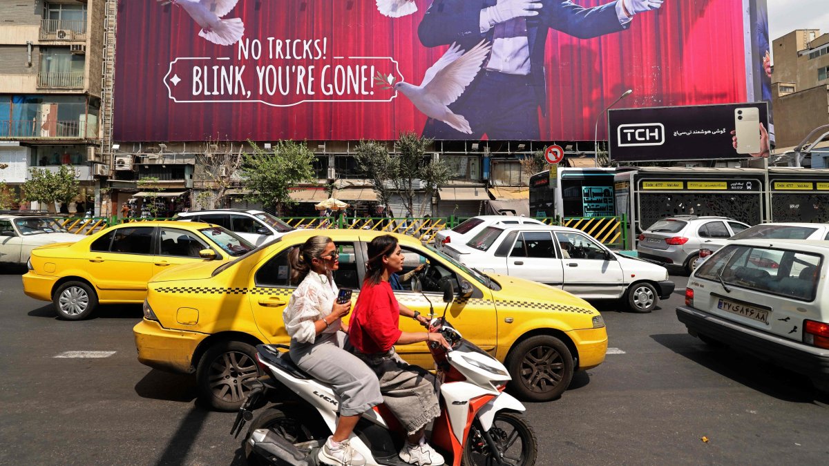 Commuters make their way past a billboard installed on a building along a busy street in downtown of Tehran, Aug. 31, 2026. (AFP Photo)
