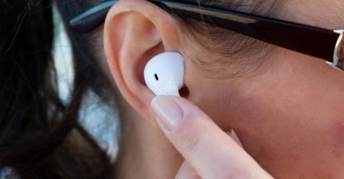 A closeup view of a girl putting on wireless earphones. (Shutterstock Photo)