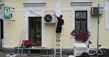 A worker installs a new air conditioning unit during a hot summer day, Belgrade, Serbia, June 30, 2026. (AP File Photo)