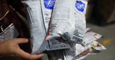 A Maharashtra Food and Drug Administration (FDA) official displays Kurkure snack packets with erased expiry dates, prices and other product details, and with new labels bearing altered ingredient information, during a raid at a warehouse, Turbhe, India, Aug. 25, 2026. (Reuters Photo)