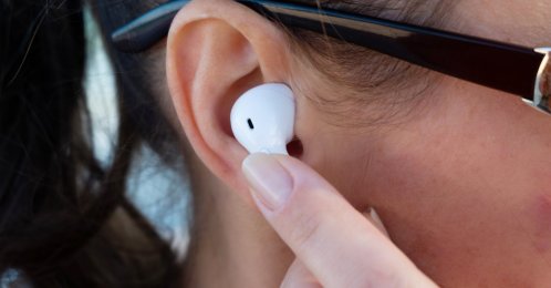 A closeup view of a girl putting on wireless earphones. (Shutterstock Photo)