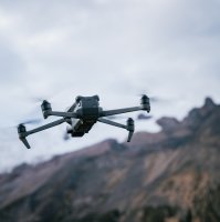A drone flies with mountain tops in the background. (Shutterstock Photo)