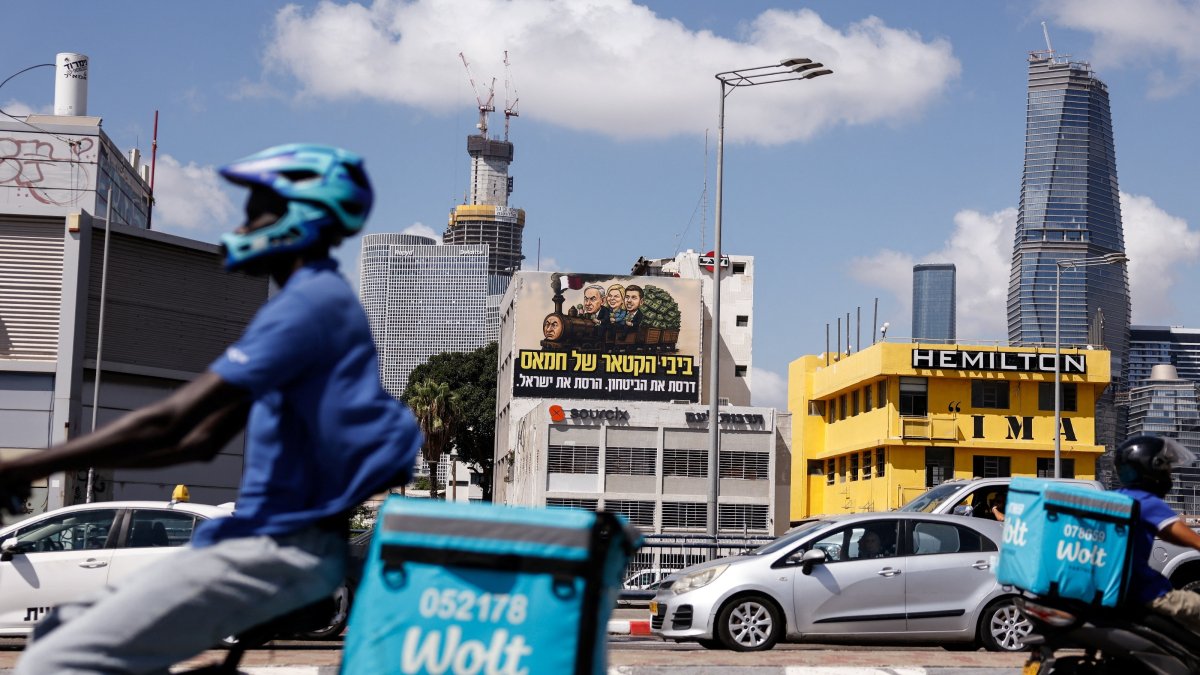 Delivery workers ride past an election billboard depicting Benjamşin, Sara and Yair Netanyahu with the text in Hebrew that reads "Bibi, the engine of Hamas, you ran over security - you destroyed Israel," Tel Aviv, Israel, Aug. 17, 2026. (Reuters Photo)
