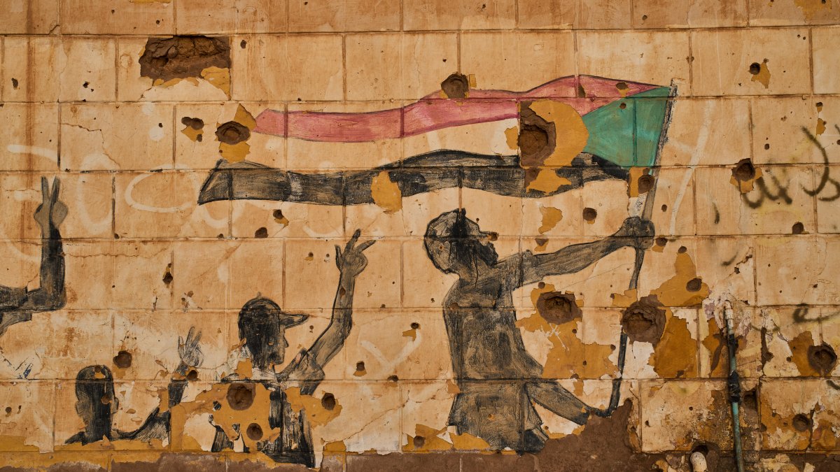 A painting depicting people holding the Sudanese flag is seen on a wall damaged by bullets and shrapnel in Omdurman, on the outskirts of Khartoum, Sudan, April 23, 2026. (AP Photo)