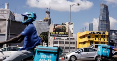 Delivery workers ride past an election billboard depicting Benjamşin, Sara and Yair Netanyahu with the text in Hebrew that reads "Bibi, the engine of Hamas, you ran over security - you destroyed Israel," Tel Aviv, Israel, Aug. 17, 2026. (Reuters Photo)