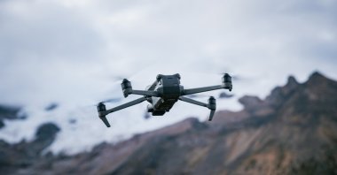 A drone flies with mountain tops in the background. (Shutterstock Photo)