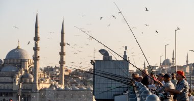 Fishermen cast their lines from Galata Bridge with Yeni Mosque seen in the background, Istanbul, Türkiye, Aug. 7, 2026 (Reuters Photo)