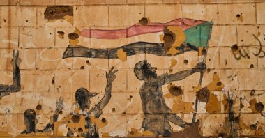 A painting depicting people holding the Sudanese flag is seen on a wall damaged by bullets and shrapnel in Omdurman, on the outskirts of Khartoum, Sudan, April 23, 2026. (AP Photo)