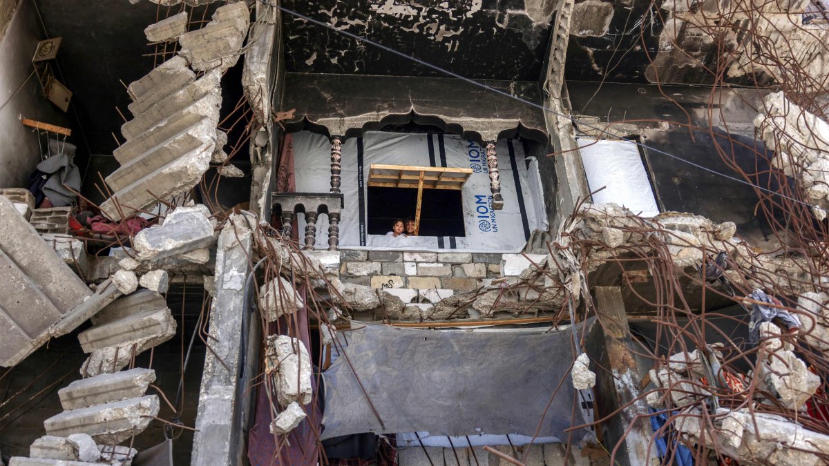 Children look out of the window of a makeshift shelter amidst the rubble of a heavily-damaged building in Khan Younis in the southern Gaza Strip, Aug. 25, 2026. (AFP Photo)
