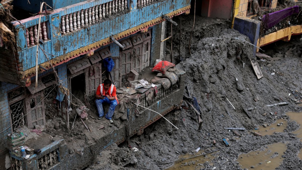 A man uses his mobile phone as he sits outside a damaged house following the deadly flash floods and mudslides in Devighat, Nuwakot district, Nepal, Sept. 5, 2026. (Reuters Photo)