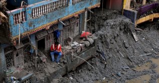 A man uses his mobile phone as he sits outside a damaged house following the deadly flash floods and mudslides in Devighat, Nuwakot district, Nepal, Sept. 5, 2026. (Reuters Photo)
