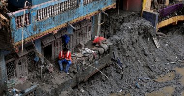 A man uses his mobile phone as he sits outside a damaged house following the deadly flash floods and mudslides in Devighat, Nuwakot district, Nepal, Sept. 5, 2026. (Reuters Photo)